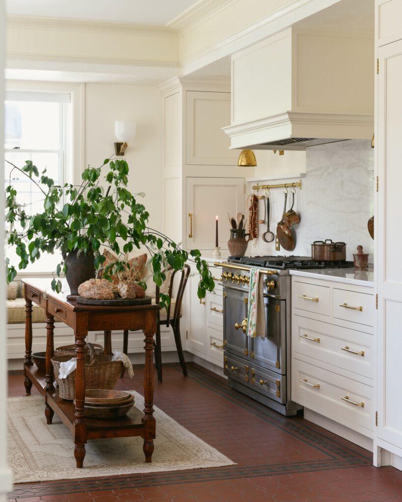 A new kitchen space by Cruze Architects with Drury Cabinetry in white, a metallic stove, and plants on the dining table.