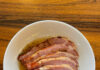 Celebrate Easter with Brunch, Dinner, and Take-Out Options in Pittsburgh Slices of Easter ham on a white plate on a wood table.