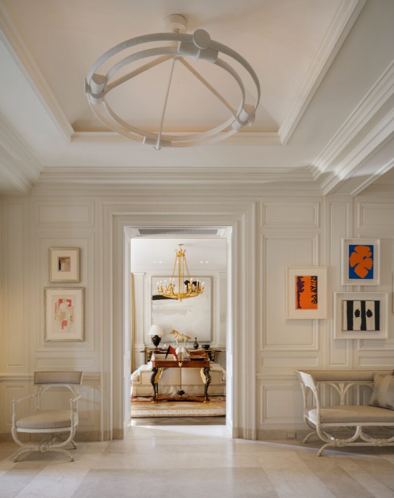 A modern and historic living room interior design by Féau Boiseries with white walls and paintings with pops of color.