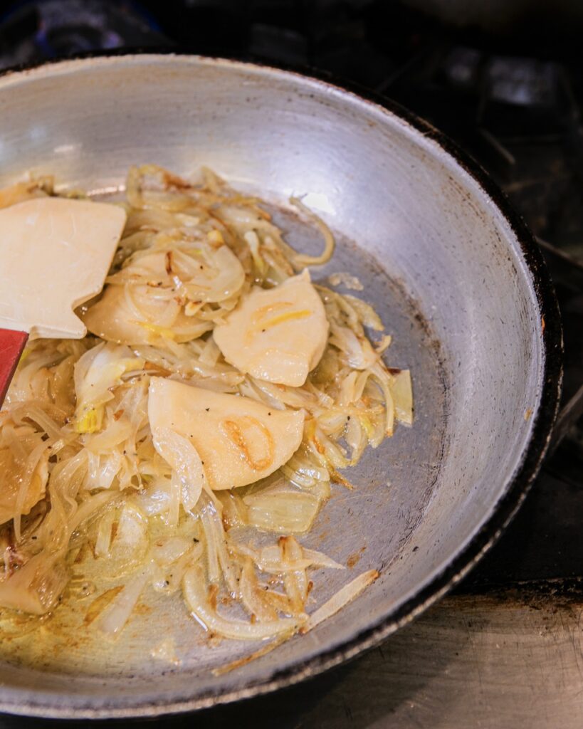 Pierogies and onions sit in a frying pan.
