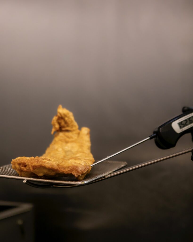 A person pulls fish out of a fryer.