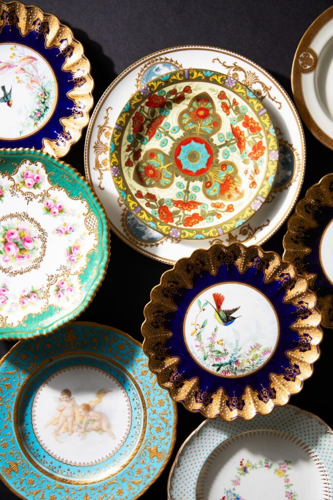 Various china plates from the Frick family's tableware collection have colorful patterns painted on them.
