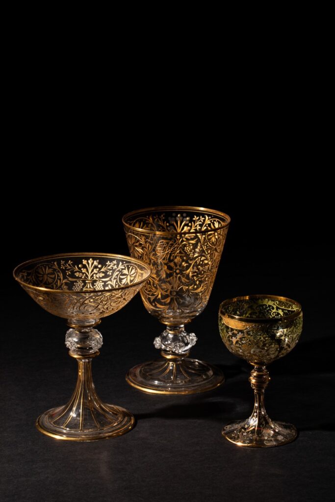 Three golden gilded goblets as a part of Frick's tableware collection sits on a black background.