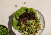 Green Goddess Pea, Bacon, and Cheddar Salad A white bowl holds butter lettuce leaves with plenty of peas, cheddar cheese, and bacon. Off to the bottom right corner sits a bowl of green goddess dressing.