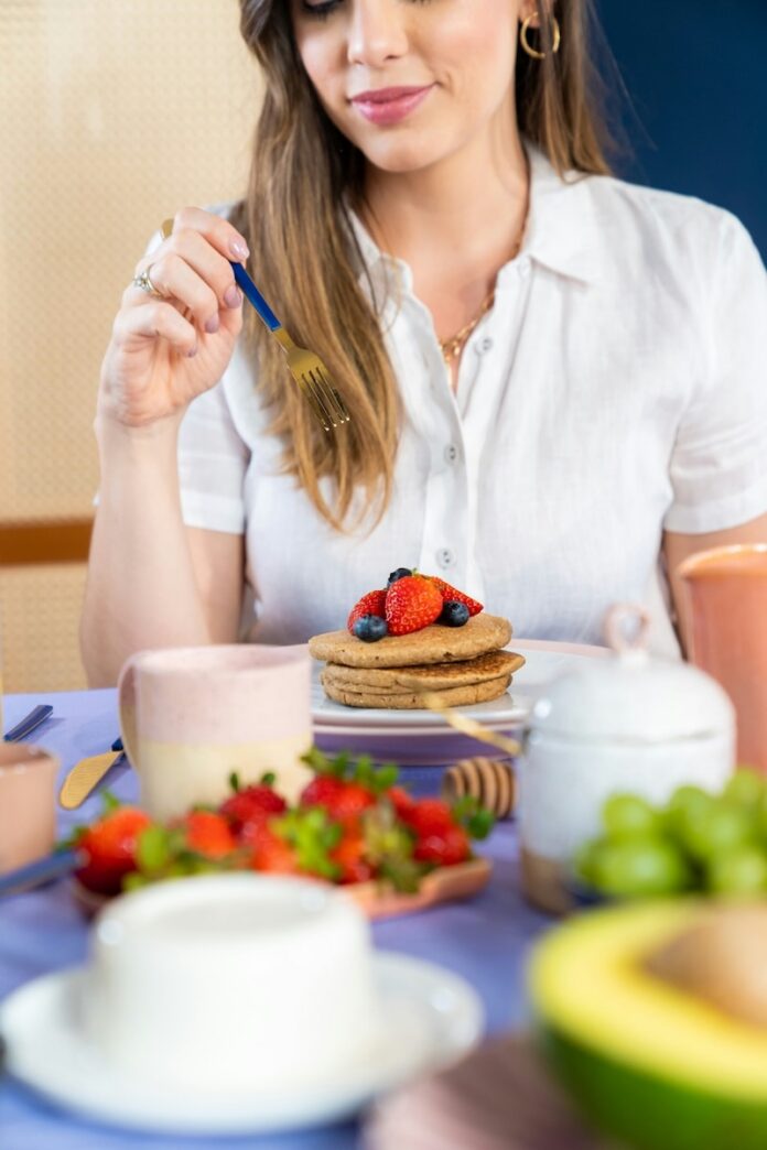 Mother's Day Brunch Pittsburgh TABLE Magazine A woman sits at a table with a stack of pancakes topped with fruit for brunch in front of her.