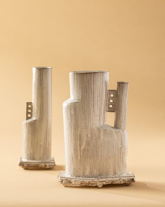 Neutral wood sculptures stand on a trendy tan background.