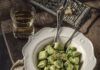 Potato and Sweet Pea Gnocchi A white bowl holds Potato and Pea Gnocchi in a green color with two forks sitting beside the bowl and bread sitting above it.