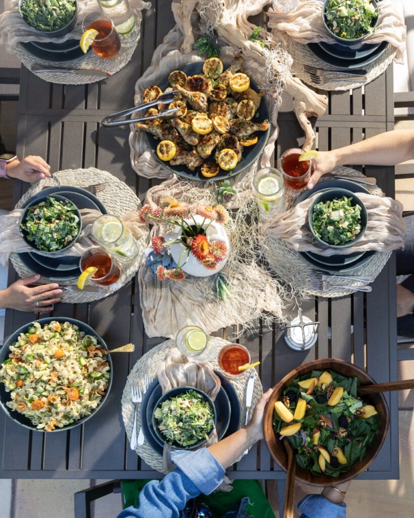 Plenty of white plates sit on a picnic table, each full of different recipes.
