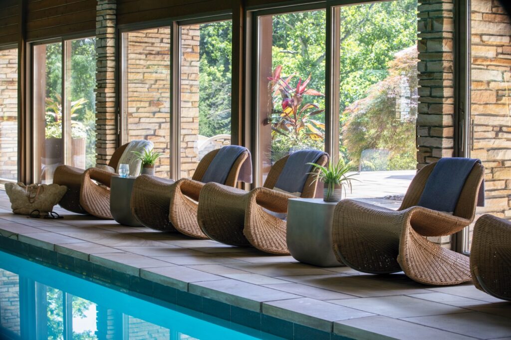 An indoor pool designed by Seashal Belldina with modern style rocking chairs along the edge.