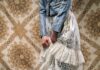 The Top Fashion Trends of Spring 2025 A woman in a white skirt pulls up her skirt to reveal black boots beneath it.