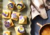 Triple Citrus Shortbread Squares Small yellow triple citrus shortbread squares link a parchment paper baking sheet with dollops of whipped cream and purple edible flowers on top.