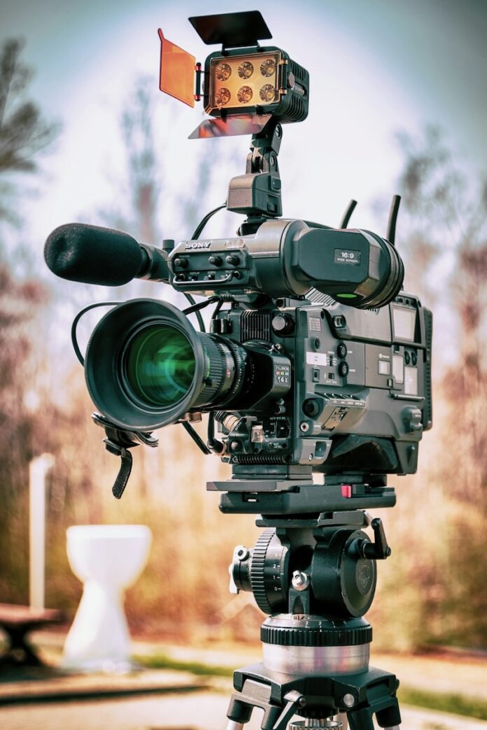 A film camera sits on a tripod in the middle of a field in the city of Pittsburgh.