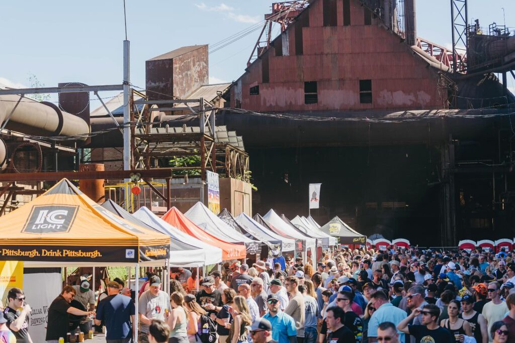 A beer festival in Pittsburgh full of crowds of people under event tents.