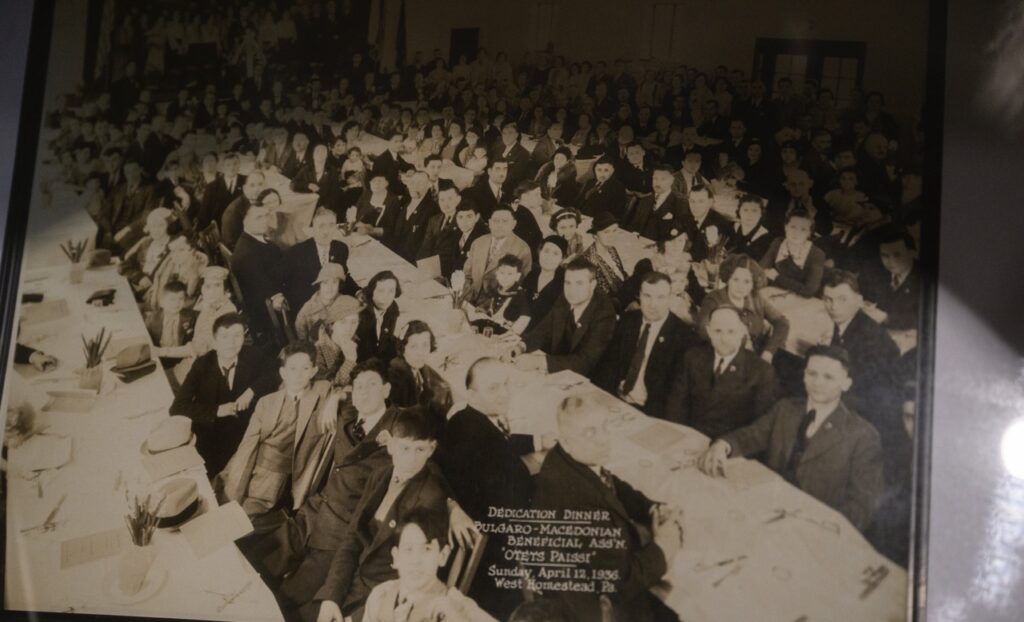 A group of people in black and white sitting at long white tables in teh Bulgarian center.