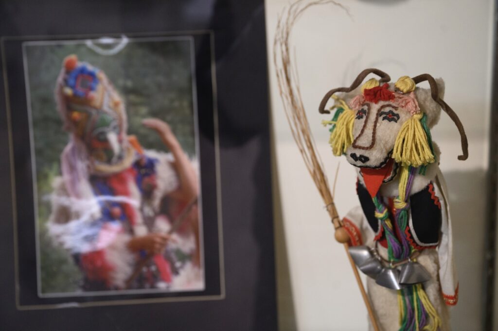 A photo in a frame sits beside an embroidered piece of Bulgarian art.