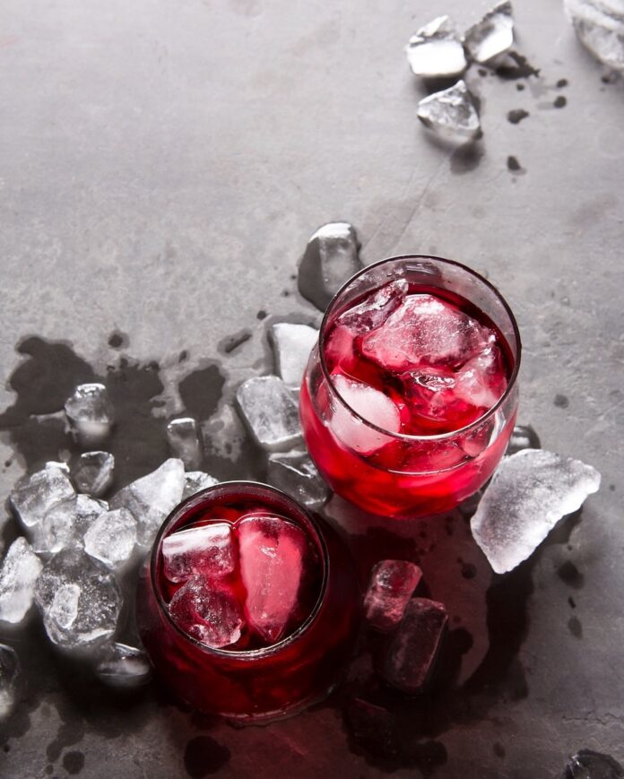 Chilled Red Wine Two glasses of chilled red wine with ice cubes in them sit on a grey table with ice cubes scattered about.