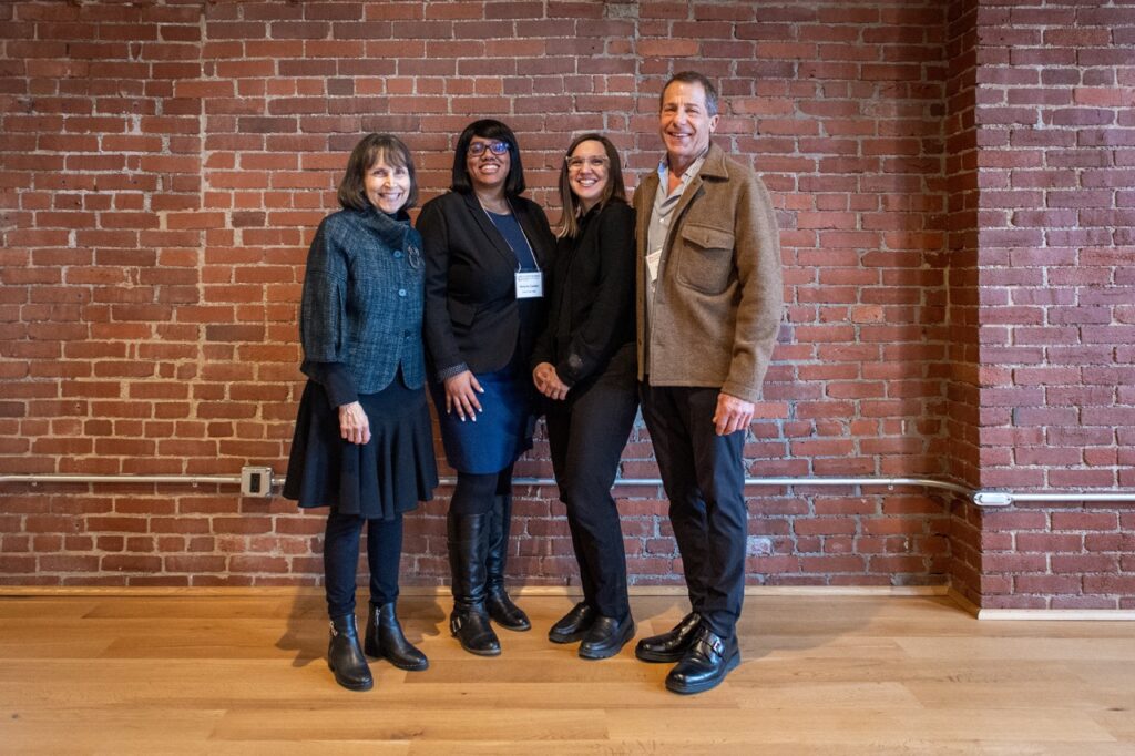Four directors at Contemporary Craft stand in front of a brick wall.