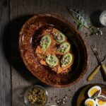 A brown platter holds orange bread squares with a fresh pea puree on top.