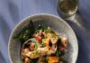 Grilled Panzanella Salad A white bowl full of a grilled Panzanella Salad with onions, tomatoes, and zucchini inside, all sitting on a blue picnic table with a spoon sitting below the bowl.