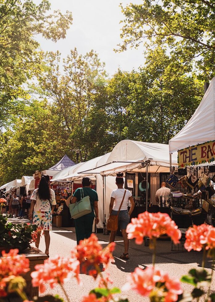 A group of three people walk through the artist market at Three Rivers Arts Festival.