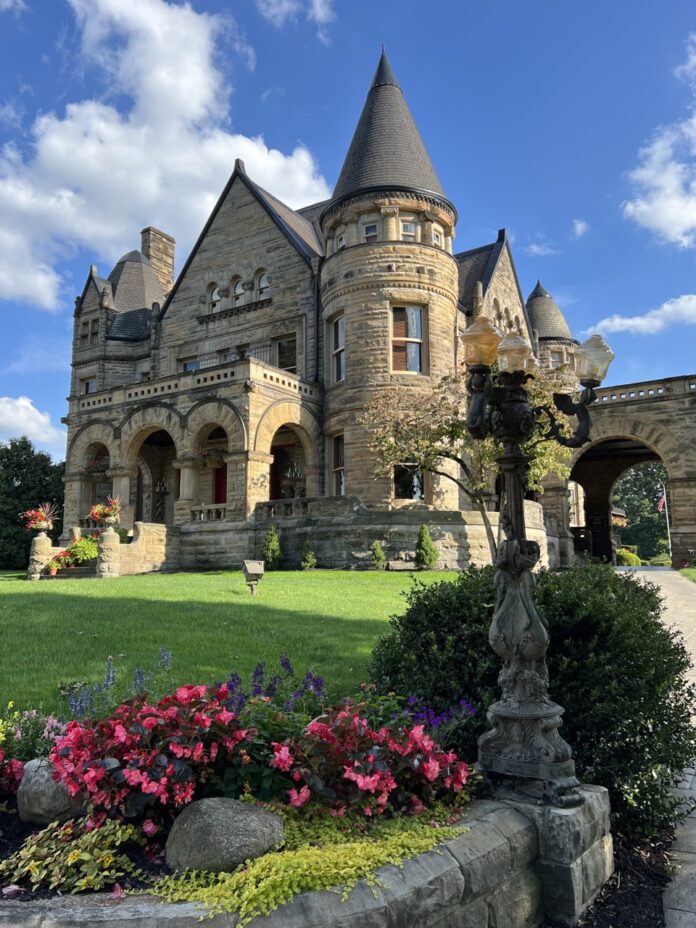 A castle historic hotel with a green lawn and flower bushes.