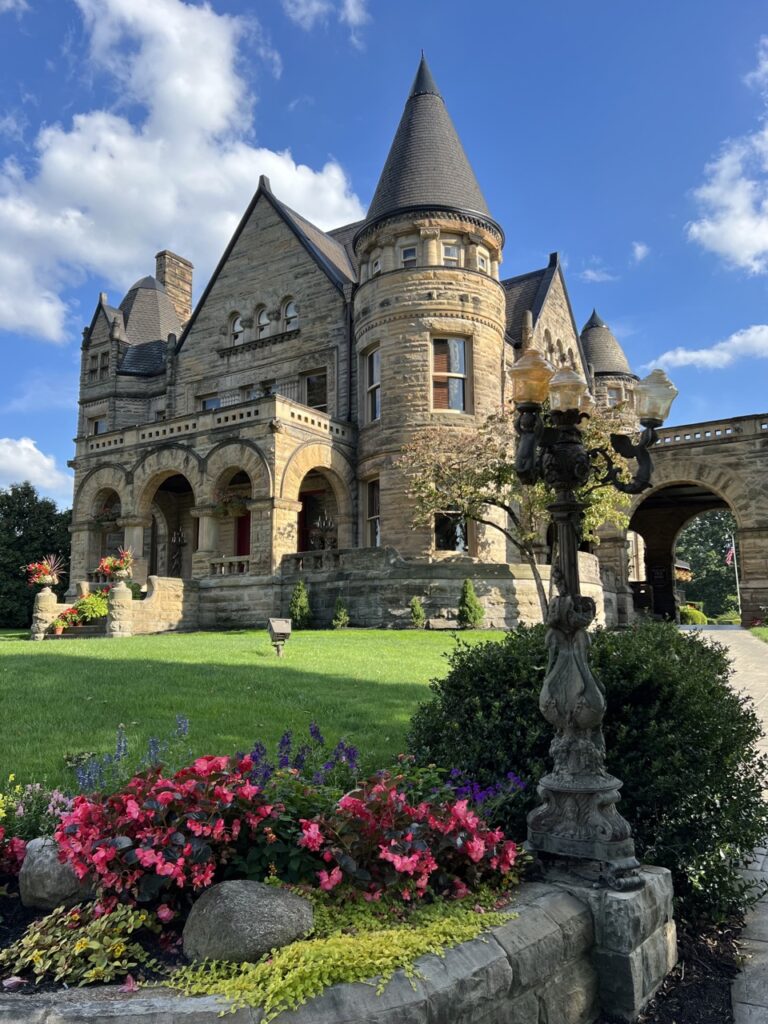 A castle historic hotel with a green lawn and flower bushes.