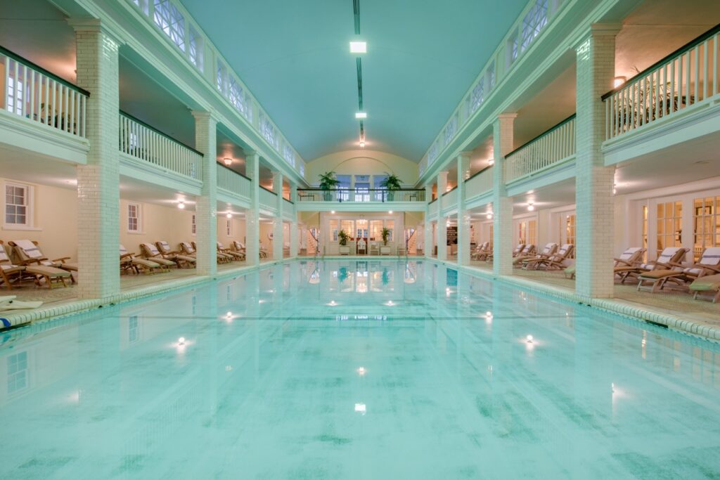 The pool inside Omni Bedford Springs Historic Hotel in Western Pennsylvania with white columns and light blue water.