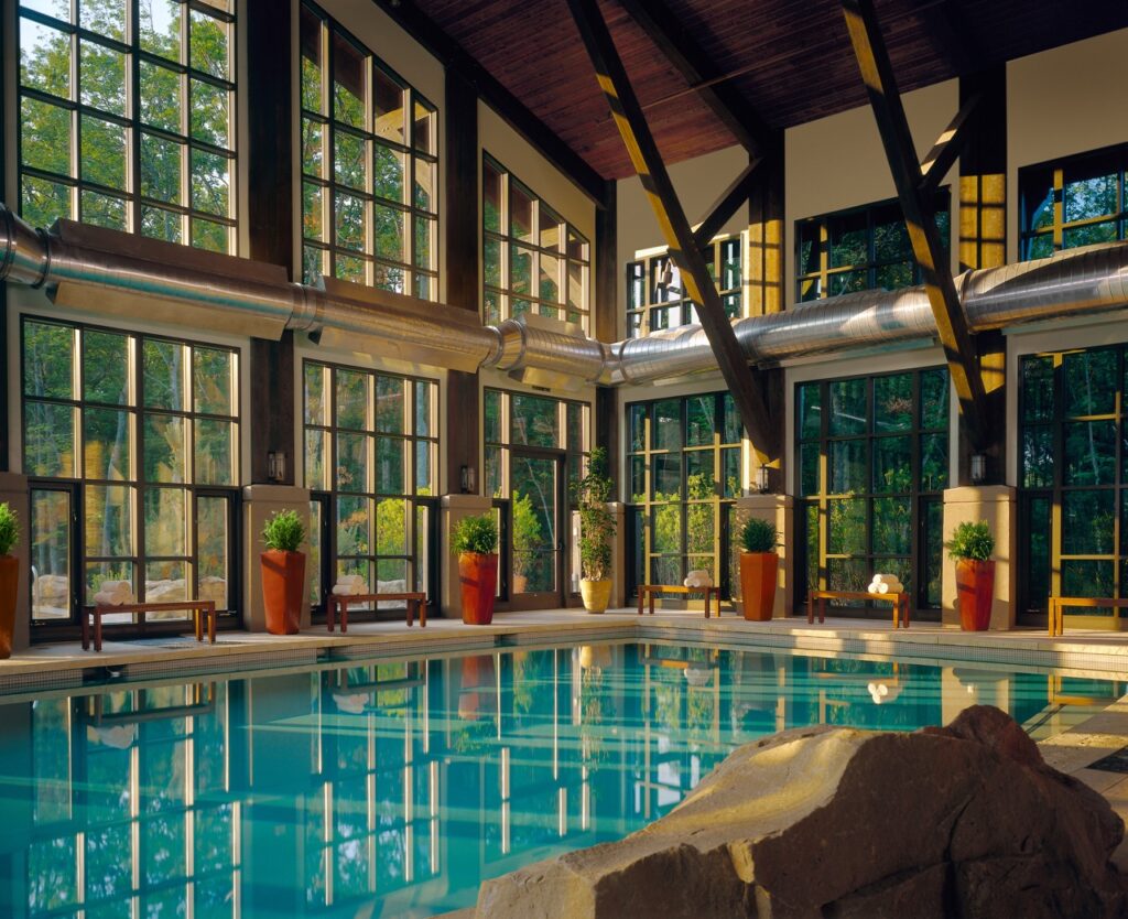 The inside of a hotel pool with large windows showing the wilderness.