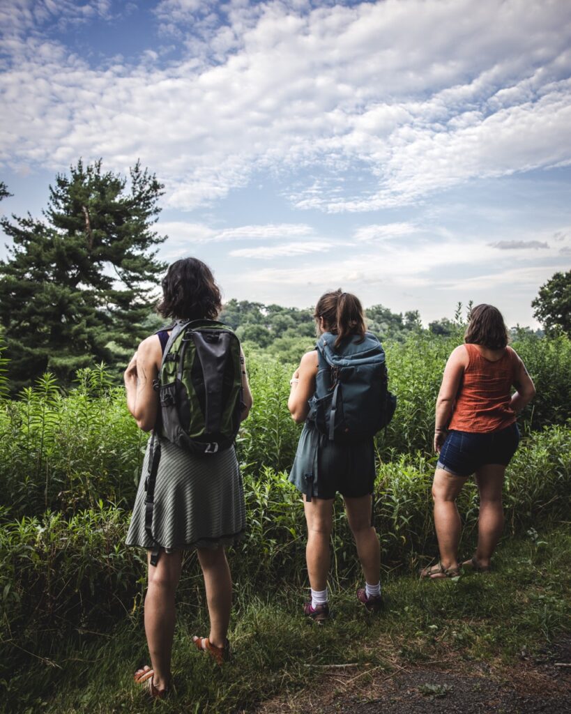 Three women stand looking out at a picnic spot in Pittsburgh's parks.
