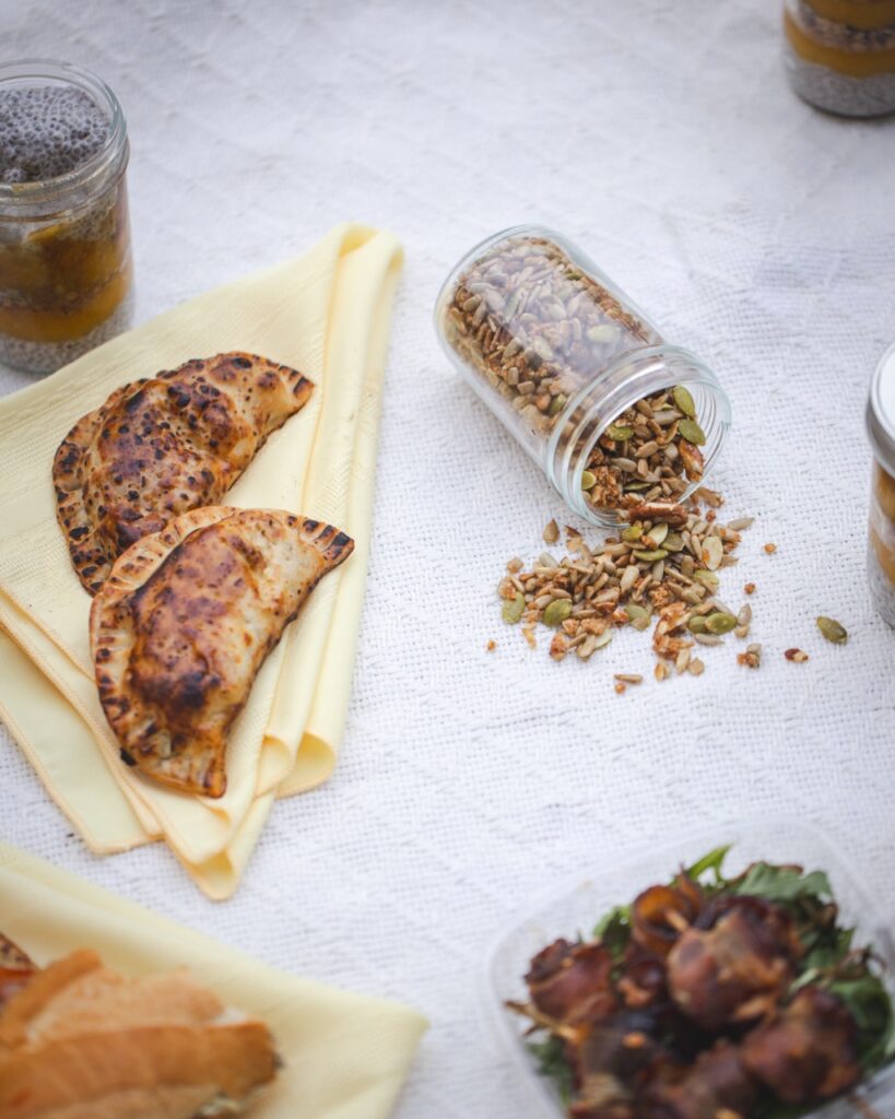 Two empanadas sit beside a granola mix spilled out from a glass jar.
