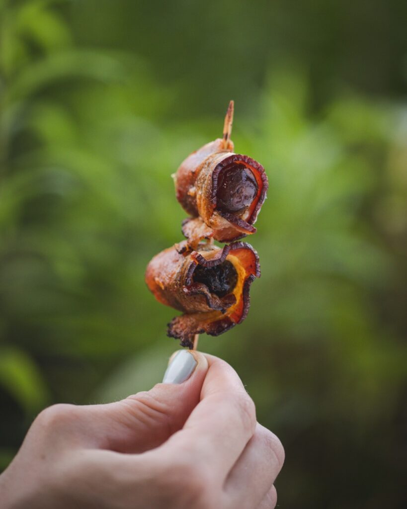 Pieces of bacon on a skewer in the outdoors.