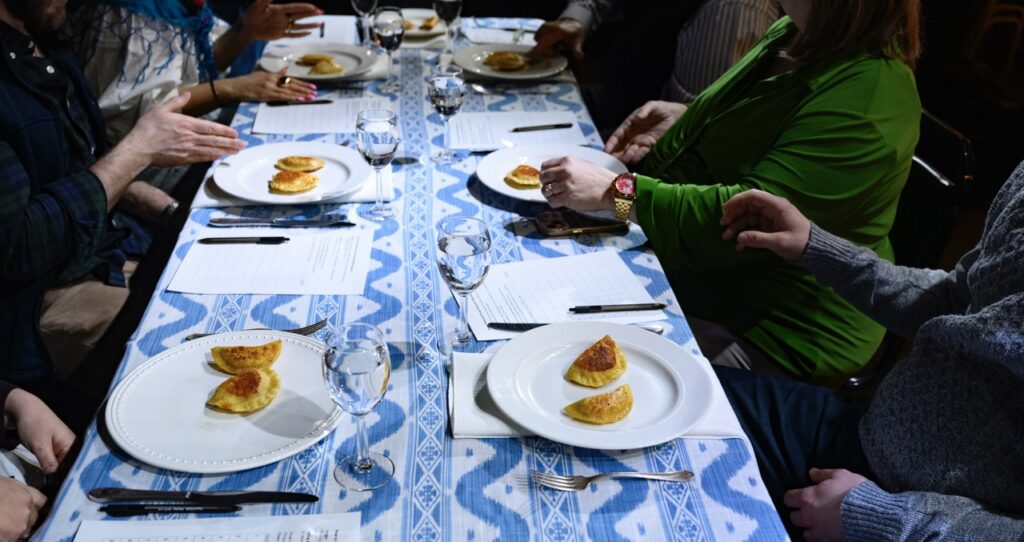 White plates with two pierogis on them sit on a blue and white table.