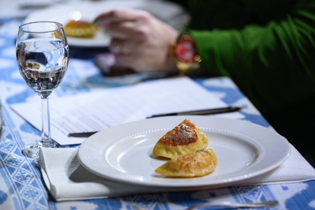 Two pierogis from Pittsburgh businesses sit on a white plate on a blue table cloth.