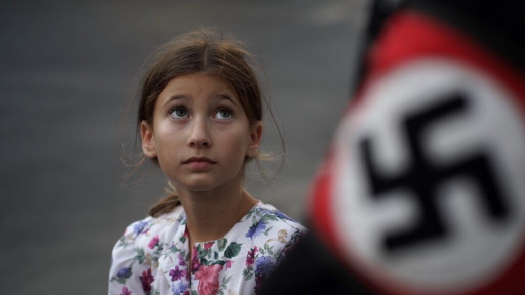 A little girl looks up at a nazi flag in a Pittsburgh short film still frame.