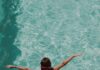 Cool Down at Pittsburgh’s Swimming Pools This Summer A girl jumps into a swimming pool with a pink and green bathing suit on.
