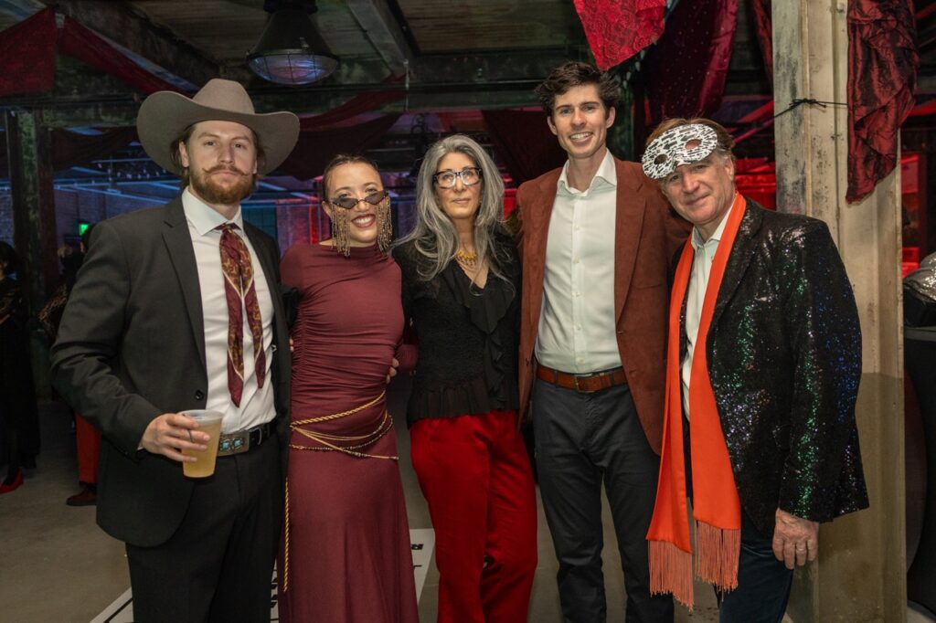 A group of five people at Quantum's Q Ball stand together arm in arm.