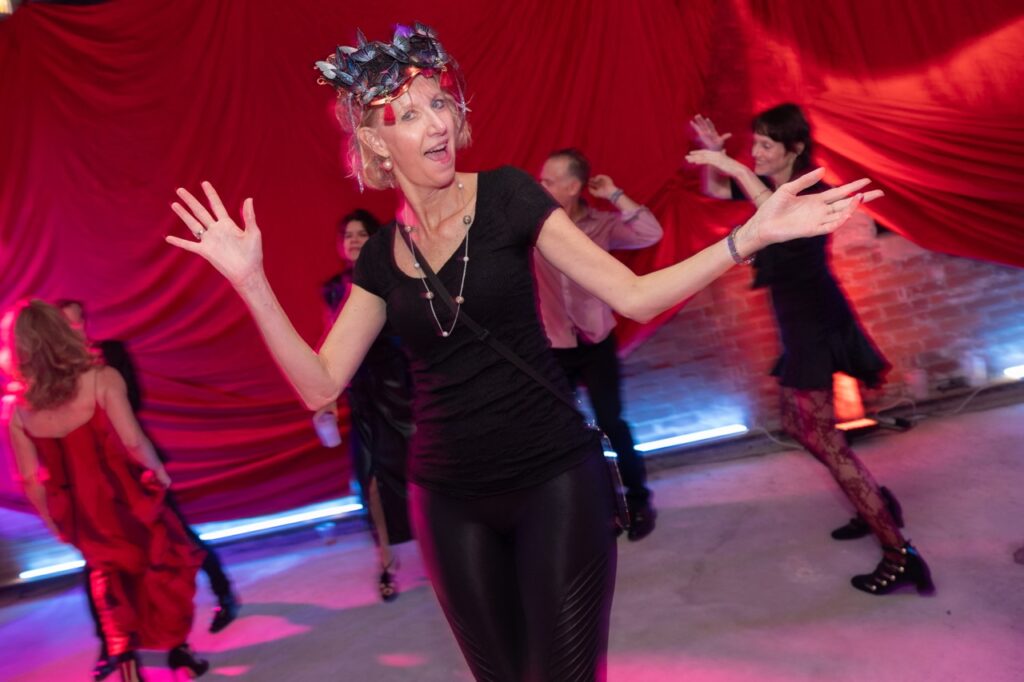 A woman dances at Quantum's masquerade ball with her mask on her forehead.