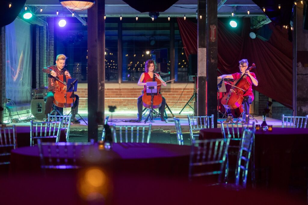 Three musicians with cellos play on Quantum's Q Ball stage.