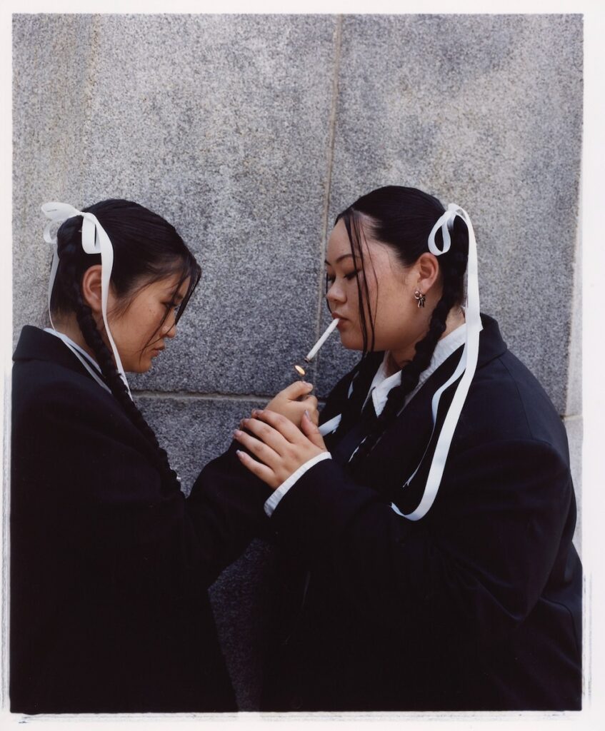 A photo of two women smoking a cigarette by Ramona Jingru Wang.
