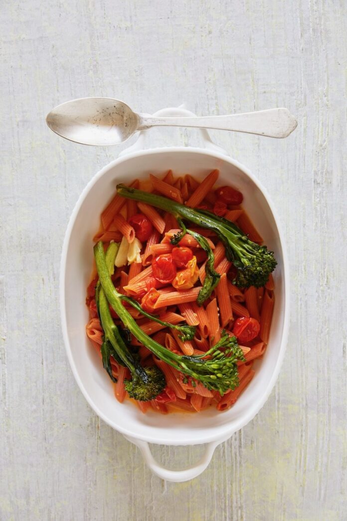 A red lentil pasta in a white dish on a white background.