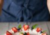 6 Recipes for a Red, White, and Blue 4th of July or Memorial Day A full gelatin cake in red, white, and blue colors decorated in strawberries, blueberries, and mint sits on a picnic like table.
