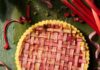 10 Rhubarb Recipes to Get You Through Springtime A whole Rhubarb Frangipane Tart with latticed rhubarb slices on top sitting on a green table with a pie spatula nearby.