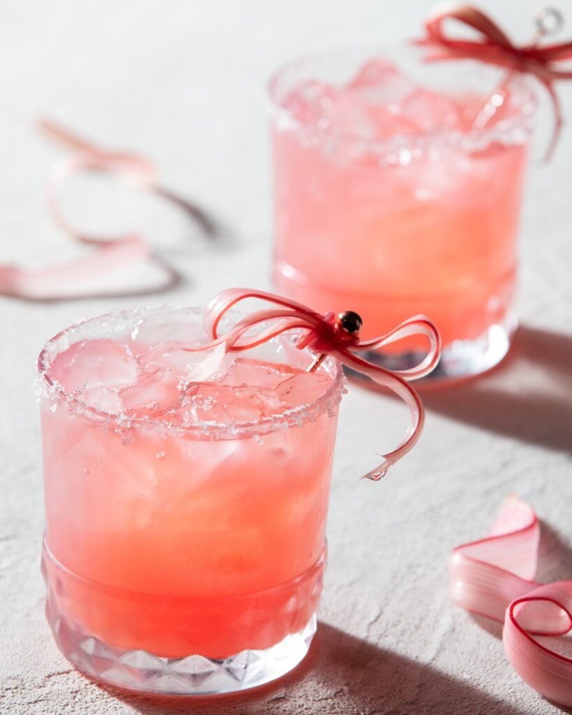 Two glasses of Rhubarb Paloma with a rhubarb ribbon garnish.