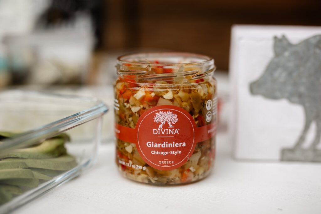 A jar of giardiniera with pickled green and red peppers and onions.