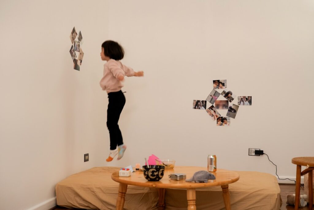 Brett Davis's daughter Toko jumps on the bed beside photographs she and her father collaborated on.