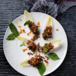 Lamb laab on a white plate on a black background.