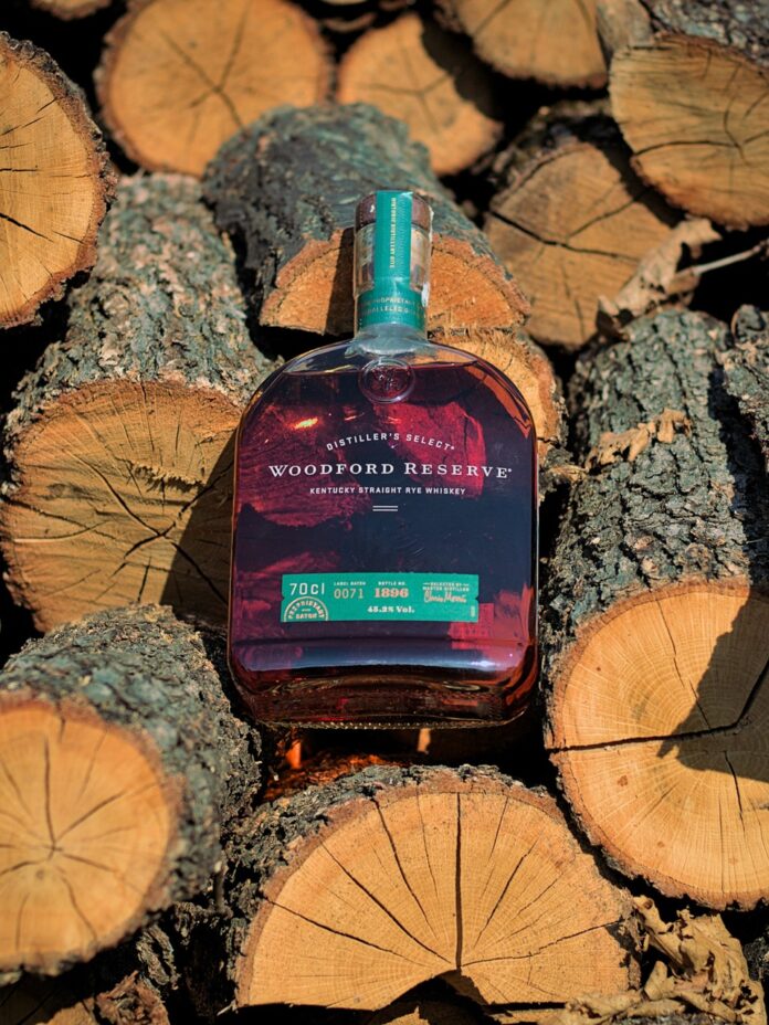 A bottle of Woodford Reserve for Father's Day sits among logs of wood.