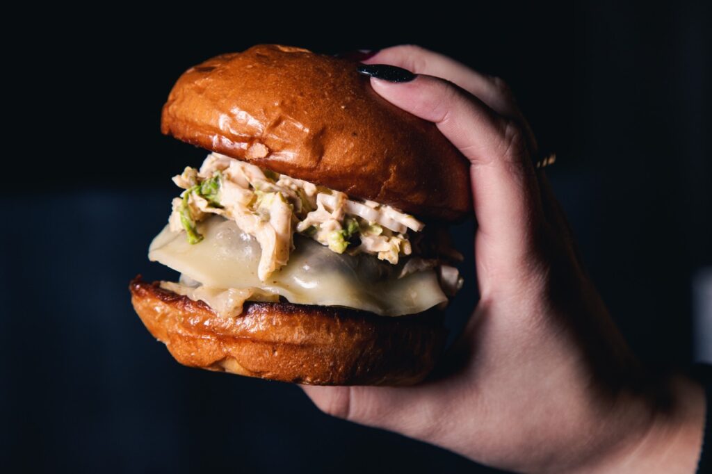A Pittsburgh burger with a bunch of sauce toppings sits in someone's hand.