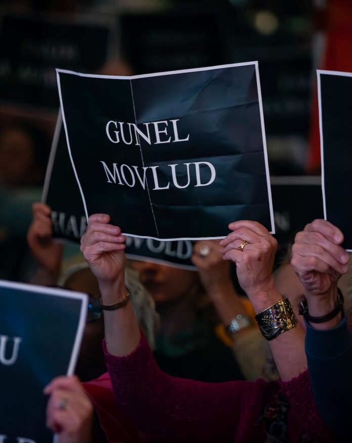 People in a crowd hold up blue signs with white names in foreign languages at City of Asylum's Creative Summit.