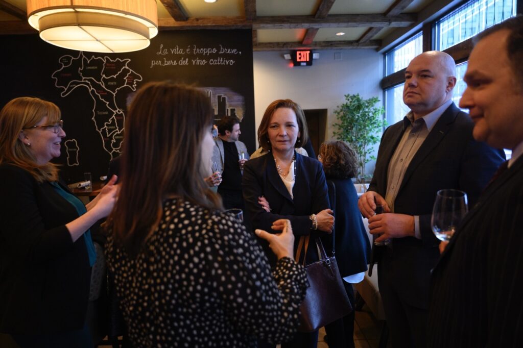 Three women and a man stand in a circle talking to each other.